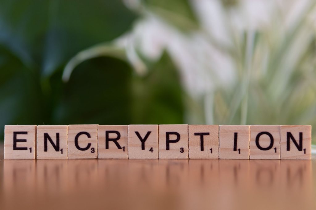 pexels-photo-30885763jpg - StakeProSoft Wooden Scrabble tiles spelling the word ENCRYPTION on a reflective surface, representing secure storage of TOTP secrets for bot automation.