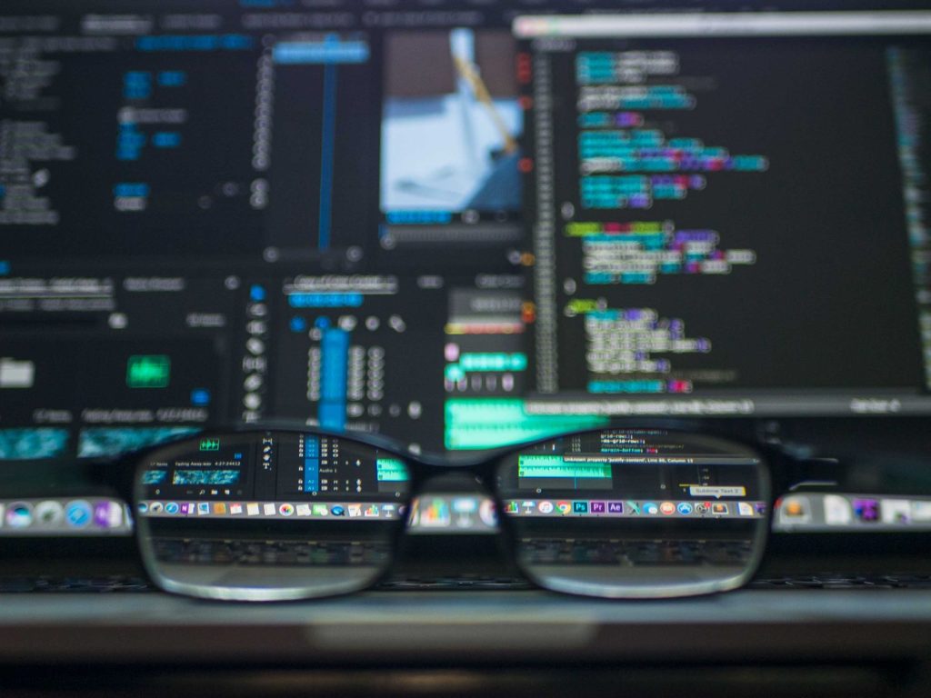 pexels-photo-577585jpg - StakeProSoft Eyeglasses resting on a keyboard reflecting colourful code on a monitor, representing the developer perspective of building 2FA-aware authentication logic.