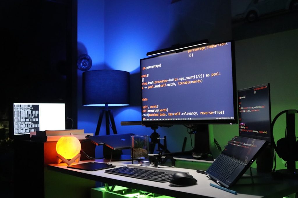 Developer workstation with large monitor displaying code terminal in a dark RGB-lit setup representing VPS bot configuration