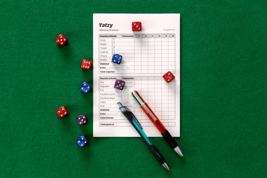 Dice scattered around a scoring scoresheet on green felt, representing betting strategy progression tracking
