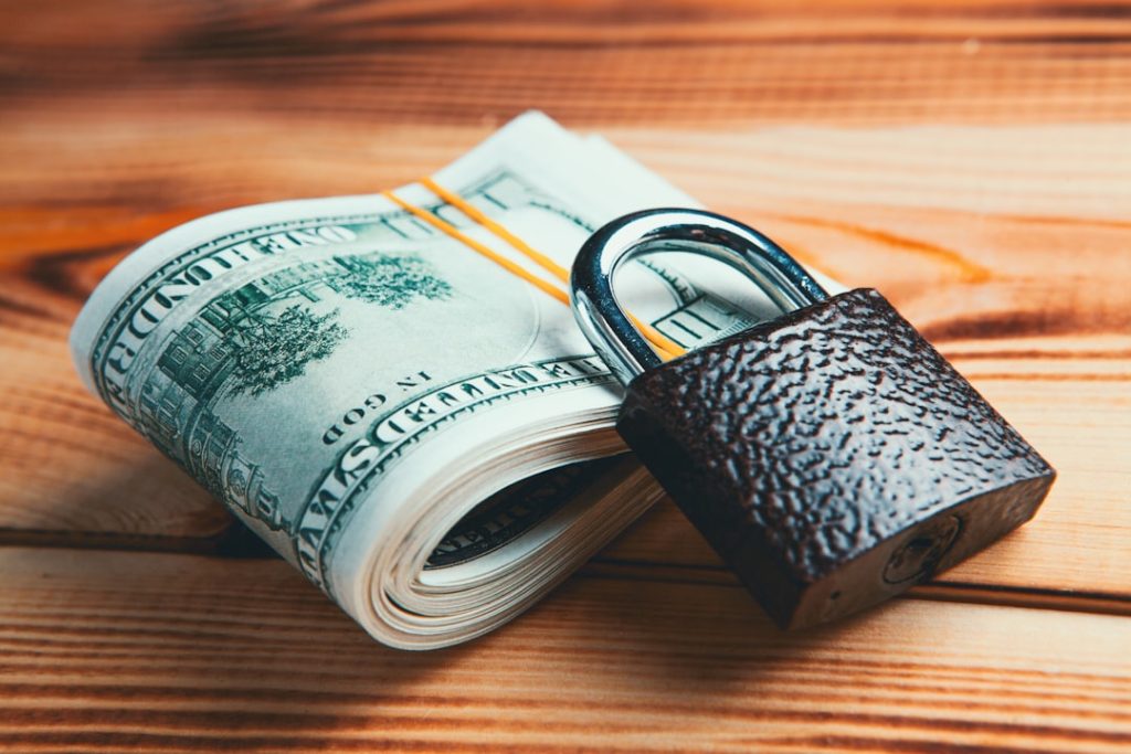 Roll of dollar bills secured with a padlock, representing bankroll protection and stop-loss limits