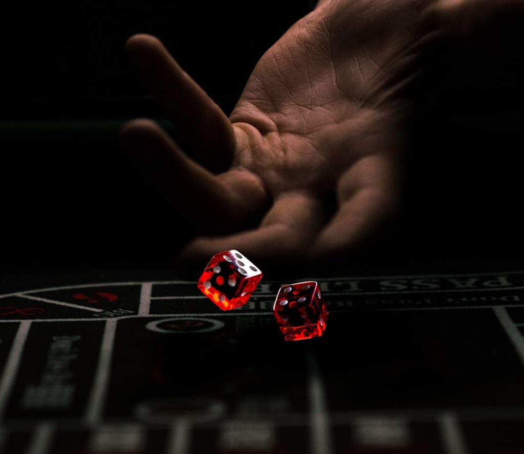 Hand throwing red dice on a casino table — Stake dice bot configuration guide